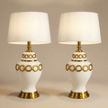 Ivory and gold table lamp pair on a beige studio background